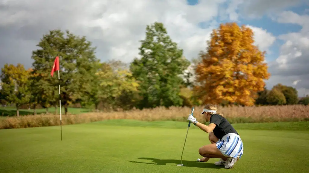 Woman lining up a putt on a golf course.