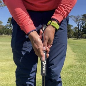 Golfer setting up for putt with conventional putting grip.