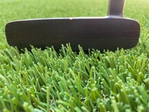 Close up of STIX putter with milled face resting on grass.