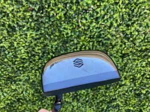 Sole of STIX putter held over grass.