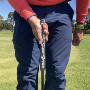 Golfer setting up for putt with only right hand on putter.