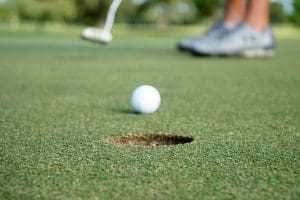 Golfer in distance putting to cup in foreground.